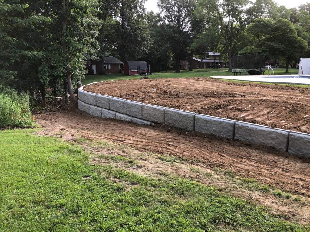 Curved concrete block retaining wall installed beside a residential swimming pool