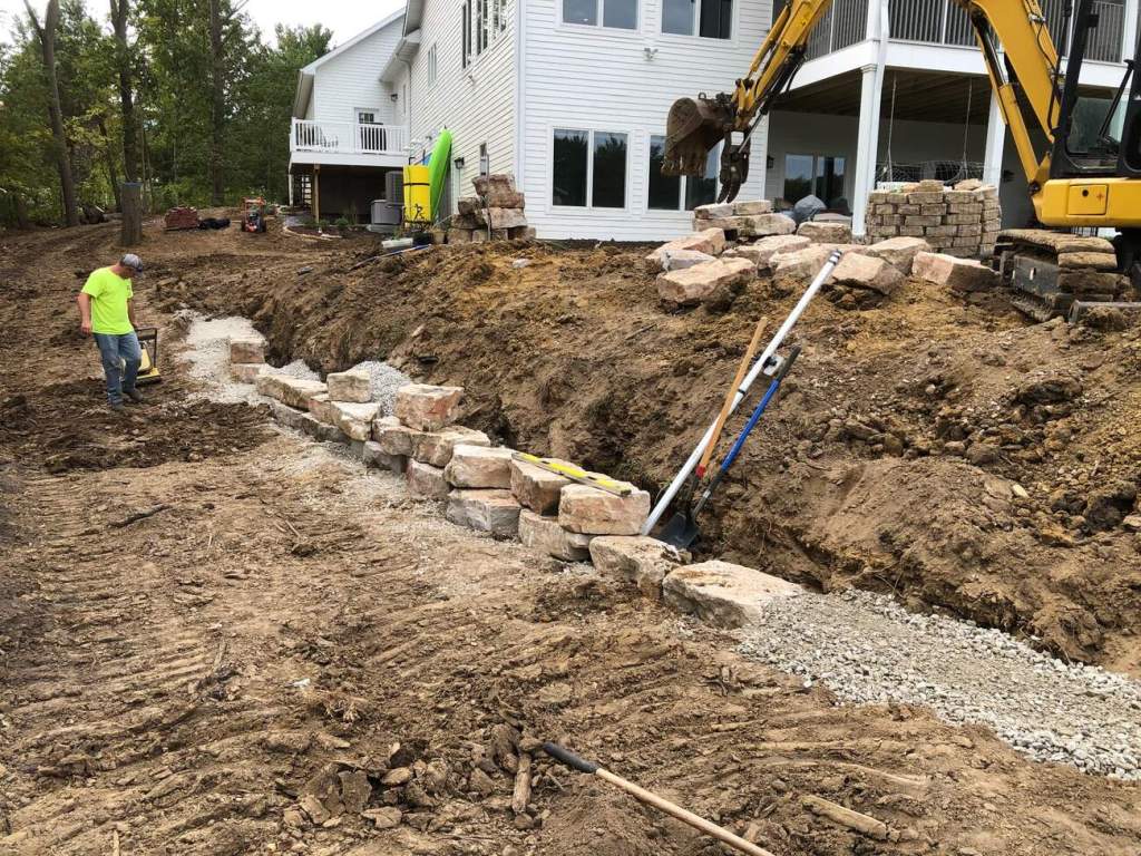 Natural stone retaining wall under construction beside a residential property
